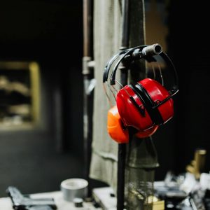 Red earmuffs on display at an indoor shooting range, emphasizing safety gear importance.